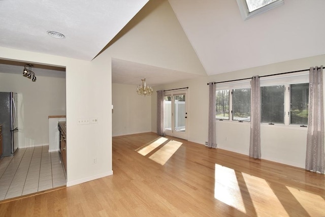 interior space with an inviting chandelier, high vaulted ceiling, baseboards, and light wood-style flooring