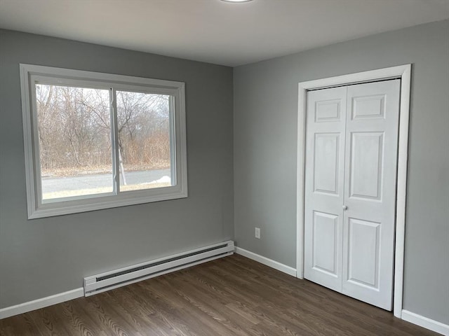 unfurnished bedroom featuring dark wood-type flooring, a closet, and baseboard heating