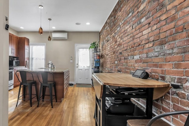 kitchen featuring pendant lighting, brick wall, sink, and gas range gas stove