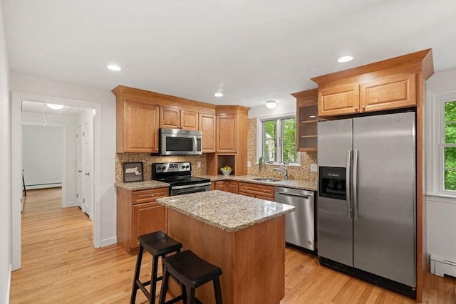 45 Fairfield St, Maynard, MA 01754 - kitchen featuring stainless steel appliances, a sink, a baseboard radiator, light stone countertops, and light wood-style floors