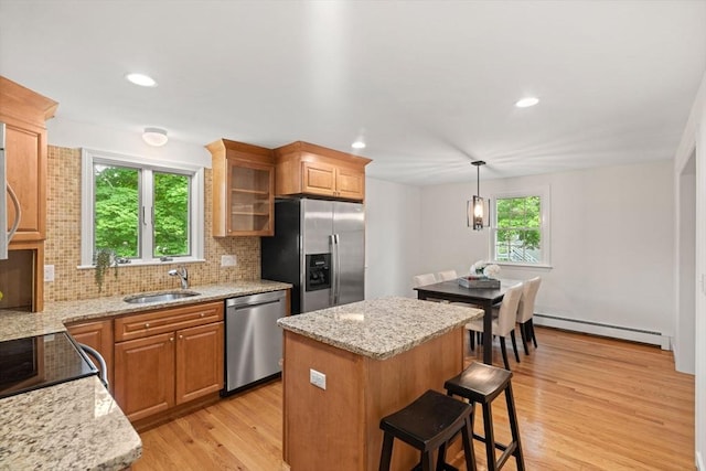 45 Fairfield St, Maynard, MA 01754 - kitchen with appliances with stainless steel finishes, a baseboard heating unit, a sink, backsplash, and light wood-style floors