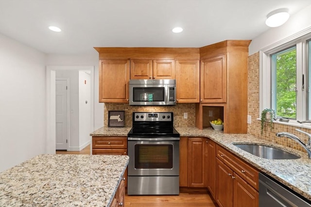 45 Fairfield St, Maynard, MA 01754 - kitchen featuring appliances with stainless steel finishes, a sink, backsplash, light stone counters, and light wood-style floors