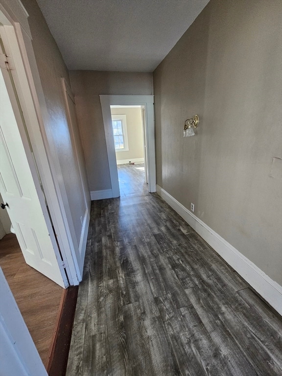 corridor with a textured ceiling and dark hardwood / wood-style flooring