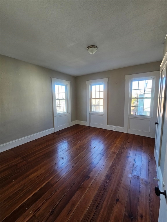 unfurnished room with dark hardwood / wood-style flooring and a textured ceiling