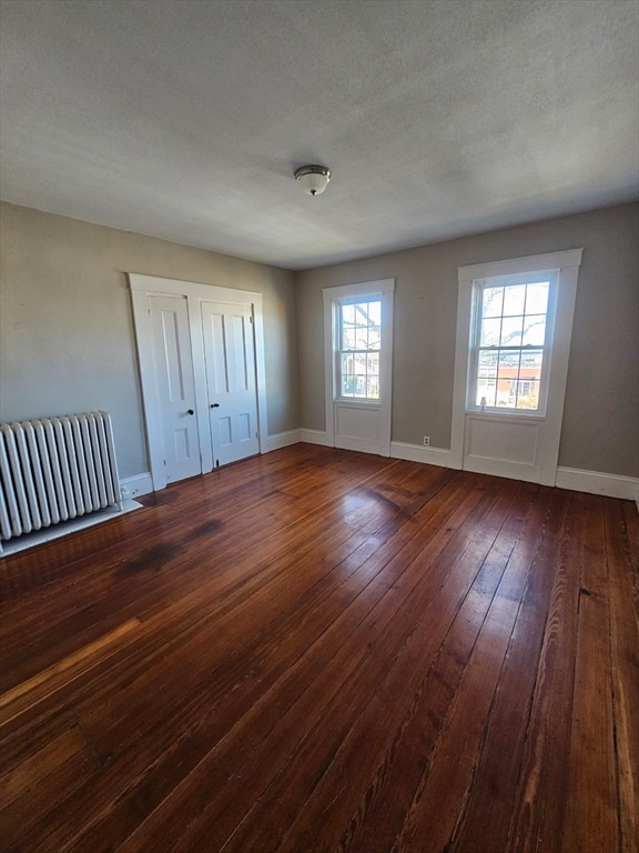 unfurnished bedroom featuring dark hardwood / wood-style flooring and a textured ceiling