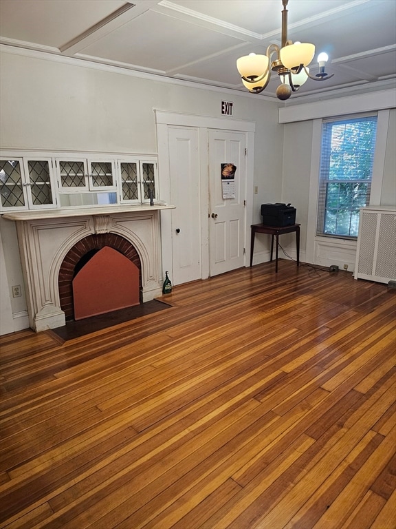 unfurnished living room featuring a fireplace, hardwood / wood-style flooring, crown molding, and a notable chandelier