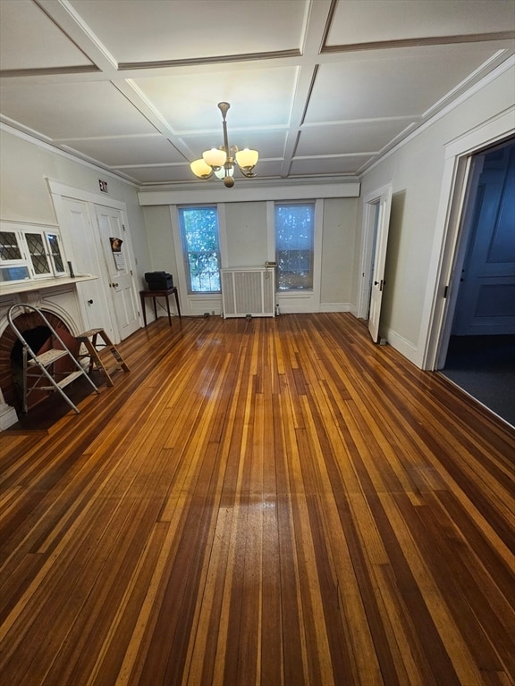 interior space featuring a fireplace, coffered ceiling, wood-type flooring, and an inviting chandelier