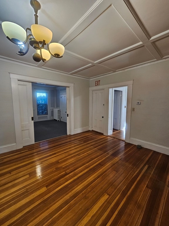 spare room featuring radiator heating unit, dark hardwood / wood-style flooring, an inviting chandelier, and coffered ceiling