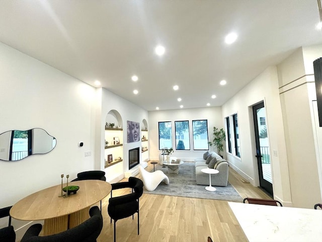 156-158 Langley Rd Unit 1, Newton, MA 02459 - living room with light wood-style floors, a glass covered fireplace, built in shelves, and recessed lighting