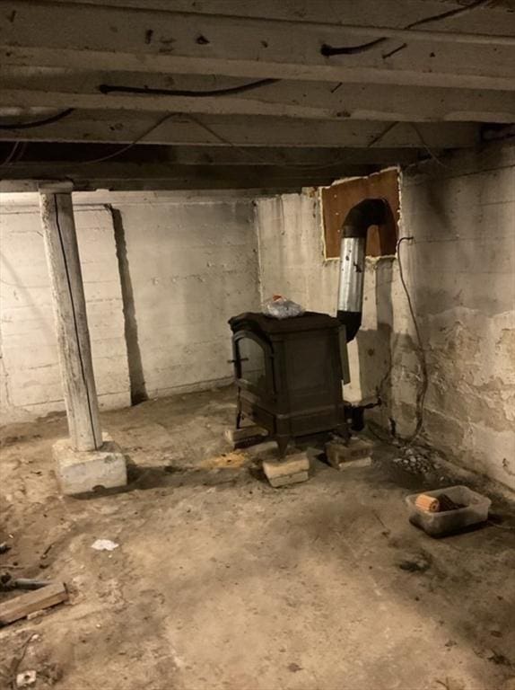 unfinished basement featuring a wood stove