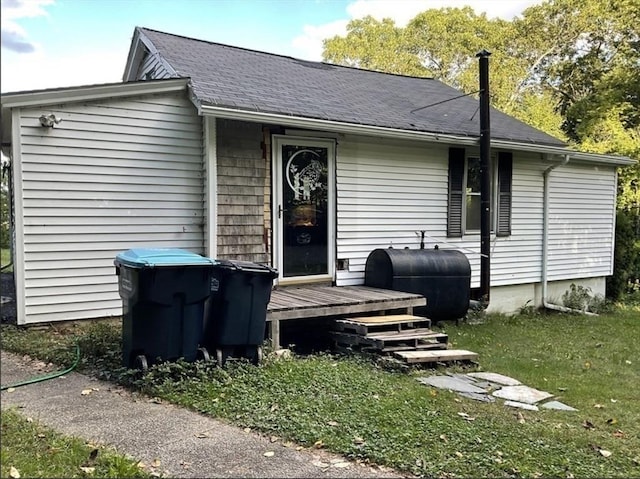 exterior space with heating fuel, a front lawn, and roof with shingles