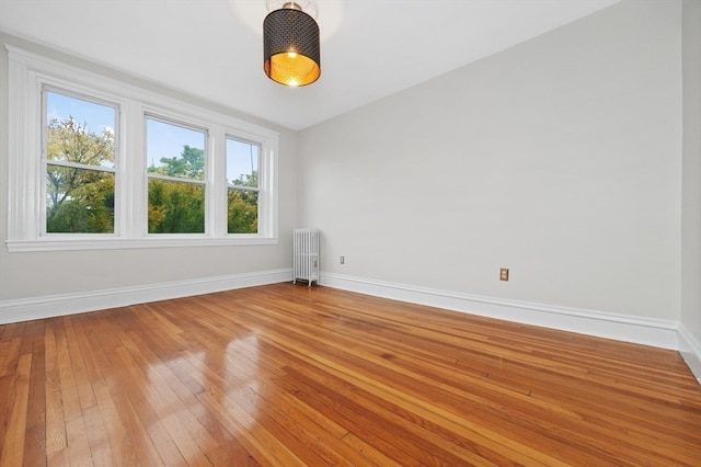 unfurnished room featuring radiator and hardwood / wood-style flooring