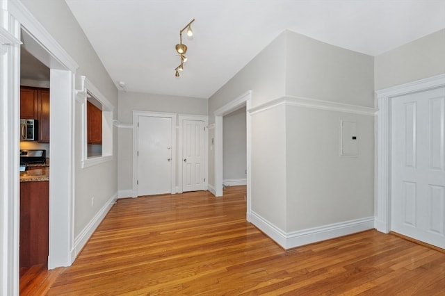 hallway with light hardwood / wood-style floors and rail lighting