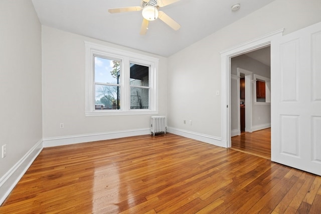 spare room featuring ceiling fan, radiator, and light hardwood / wood-style flooring