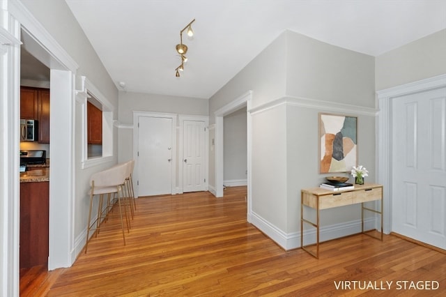 corridor with track lighting and light hardwood / wood-style flooring