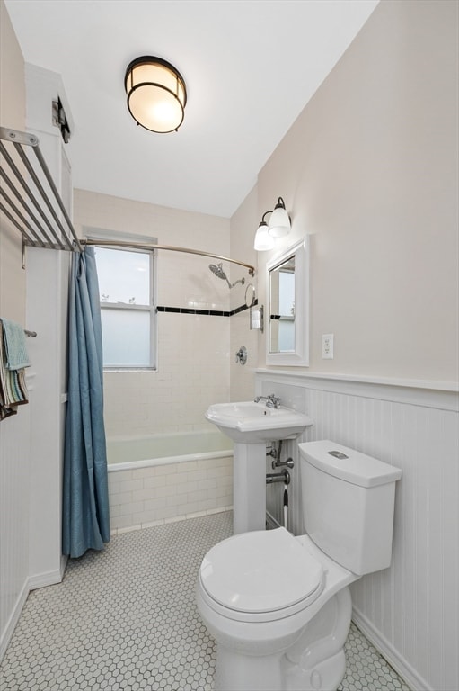 bathroom featuring shower / bath combination with curtain, tile patterned flooring, and toilet