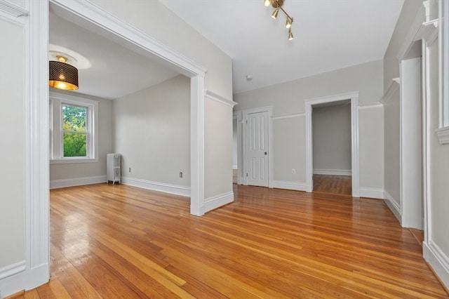 unfurnished room with radiator and light wood-type flooring