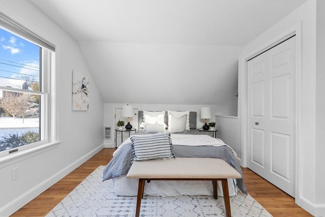 bedroom featuring baseboards, lofted ceiling, and light wood-style floors