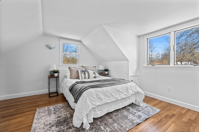 bedroom with vaulted ceiling, wood finished floors, and baseboards