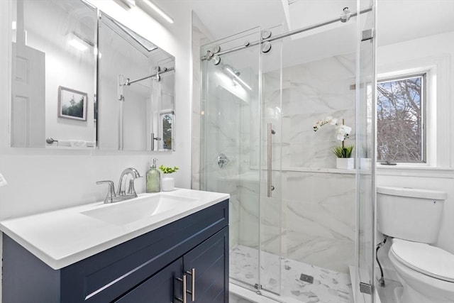 full bath featuring vanity, a marble finish shower, and toilet