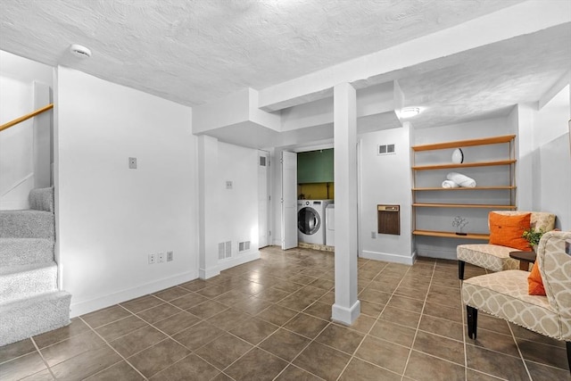 living area with visible vents, a textured ceiling, separate washer and dryer, dark tile patterned floors, and stairs