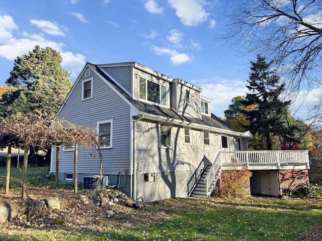 view of side of property featuring a deck, a lawn, stairway, and central AC unit