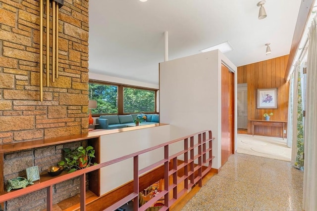 corridor featuring a towering ceiling and wood walls