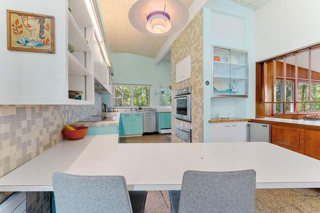 kitchen with backsplash, high vaulted ceiling, stainless steel appliances, white cabinets, and kitchen peninsula