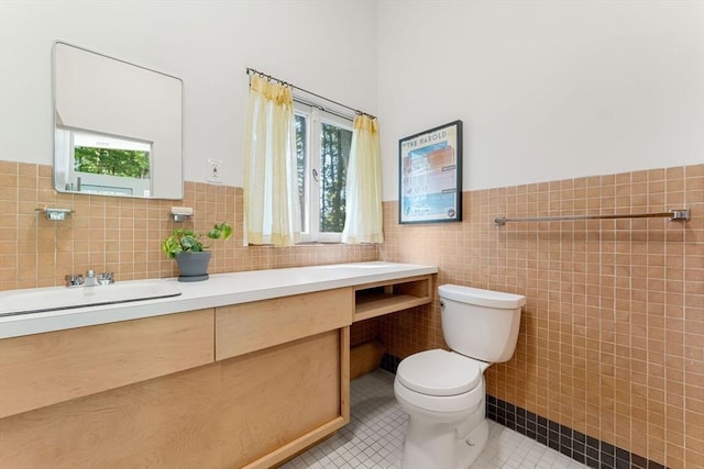 bathroom featuring tile patterned flooring, vanity, toilet, and tile walls