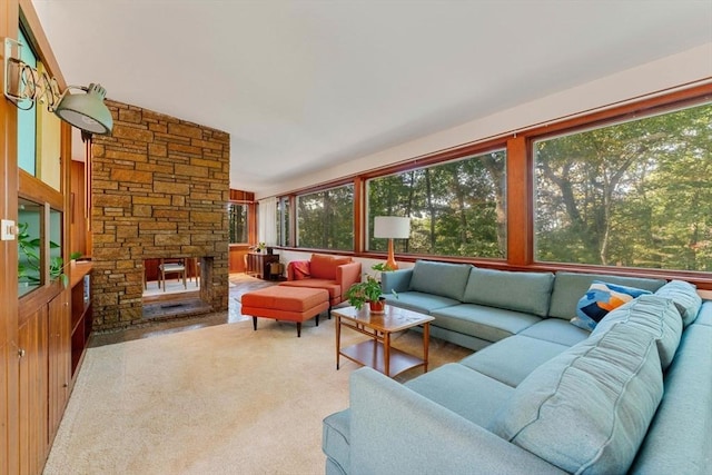 carpeted living room with a stone fireplace