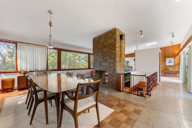 dining room with a fireplace and wooden walls