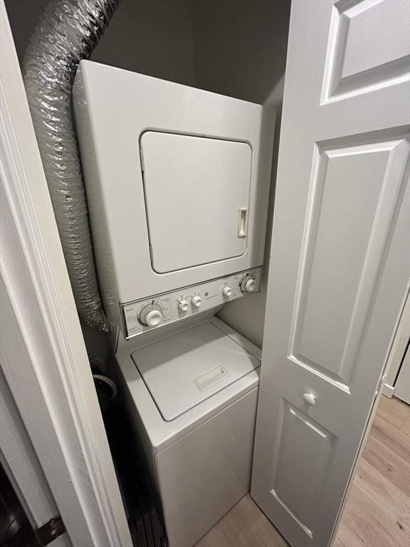 washroom with stacked washer / dryer and light wood finished floors
