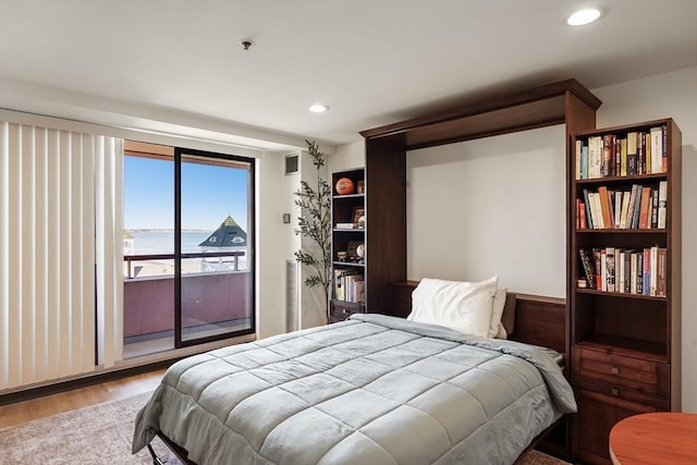 bedroom featuring access to outside, light wood-style floors, a water view, and recessed lighting