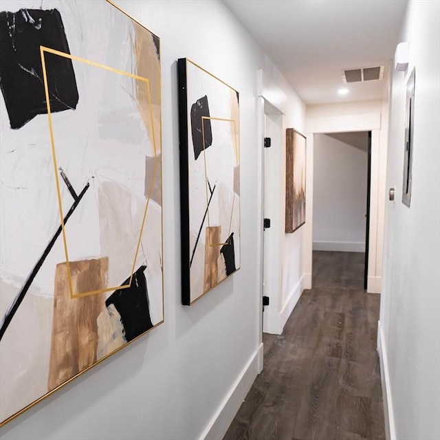 corridor featuring visible vents, baseboards, and wood finished floors