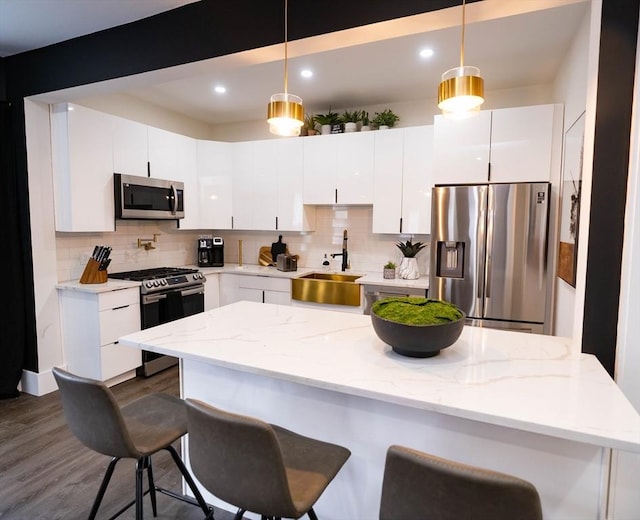 kitchen featuring a sink, appliances with stainless steel finishes, tasteful backsplash, and a kitchen bar