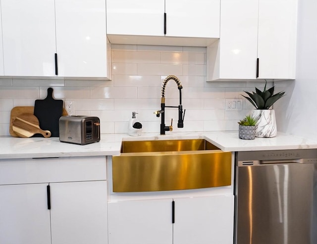 kitchen featuring backsplash, dishwasher, a sink, light stone counters, and white cabinetry