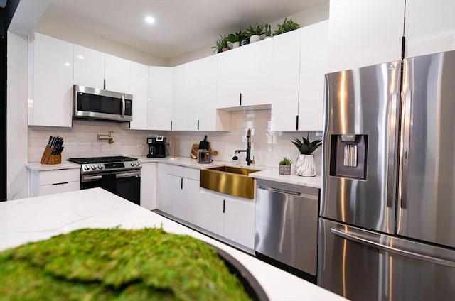 kitchen featuring white cabinets, appliances with stainless steel finishes, decorative backsplash, and a sink