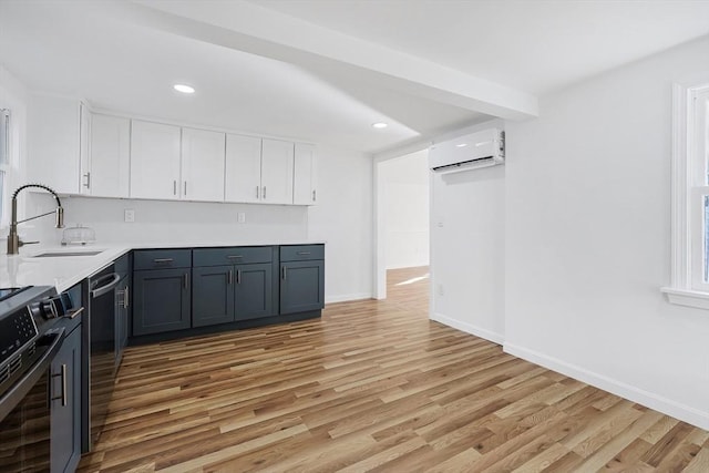 kitchen featuring light wood-type flooring, gray cabinetry, a wall mounted AC, sink, and white cabinetry