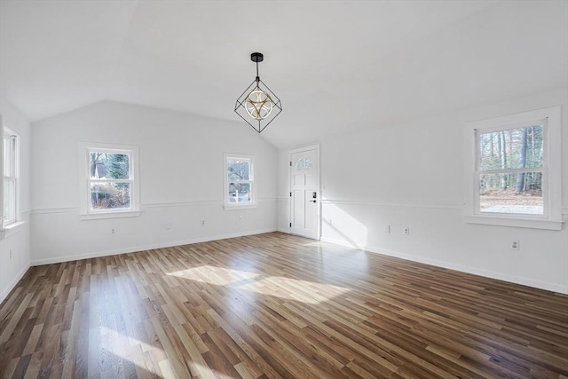 unfurnished living room with a notable chandelier, dark hardwood / wood-style floors, plenty of natural light, and vaulted ceiling