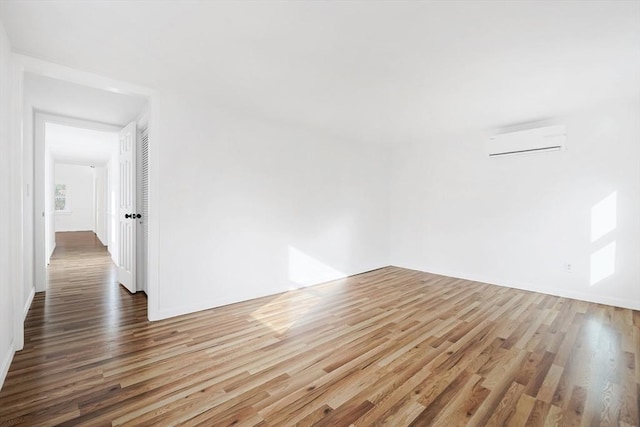 unfurnished room with a wall mounted air conditioner and wood-type flooring