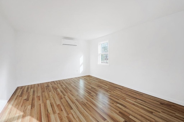 spare room with light hardwood / wood-style flooring and an AC wall unit