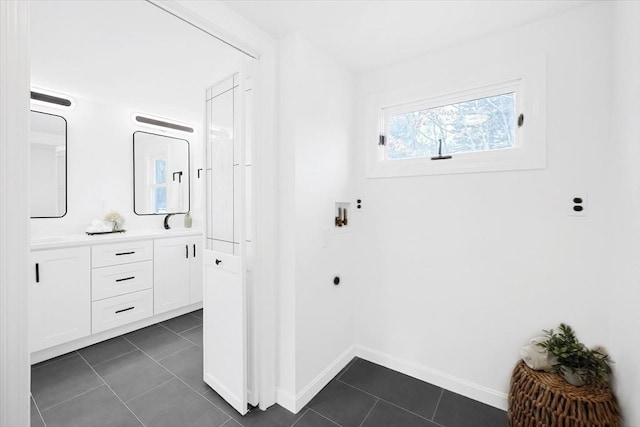 interior space featuring electric dryer hookup and dark tile patterned flooring