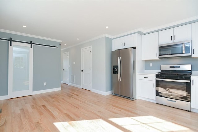 kitchen featuring crown molding, appliances with stainless steel finishes, light hardwood / wood-style floors, white cabinets, and a barn door