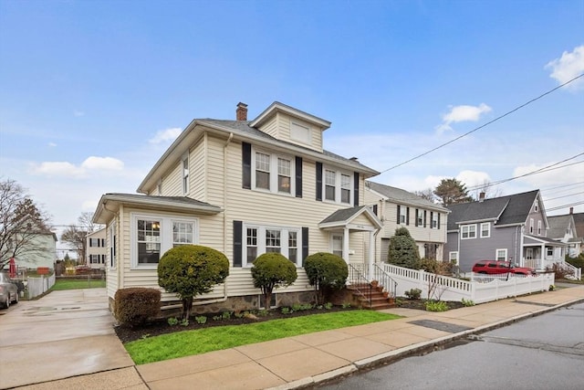 american foursquare style home featuring fence and a chimney