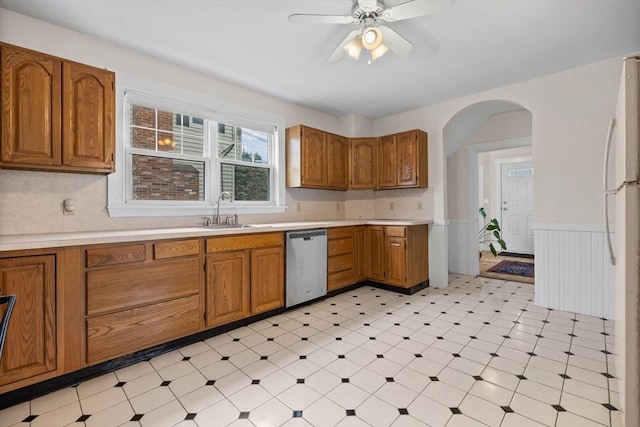 kitchen with brown cabinets, dishwasher, a sink, light countertops, and light floors