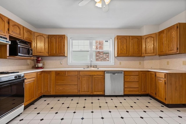 kitchen with brown cabinets, stainless steel appliances, a sink, and light floors