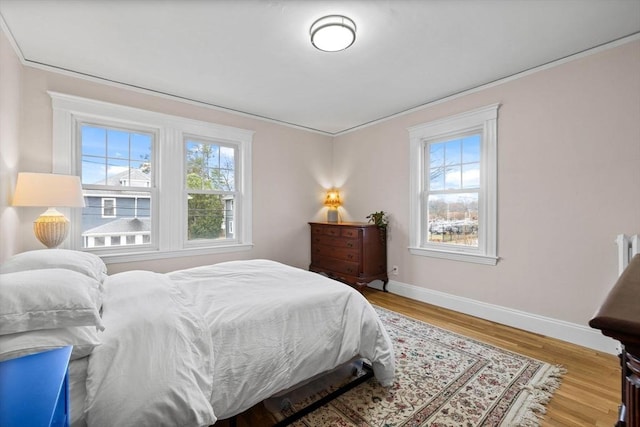 bedroom featuring baseboards, ornamental molding, and wood finished floors