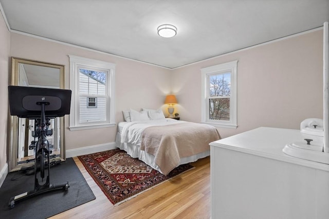bedroom featuring baseboards, ornamental molding, and wood finished floors