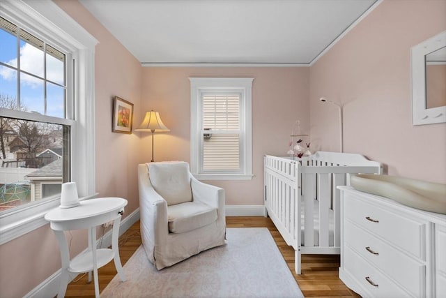 bedroom featuring baseboards, a nursery area, and wood finished floors