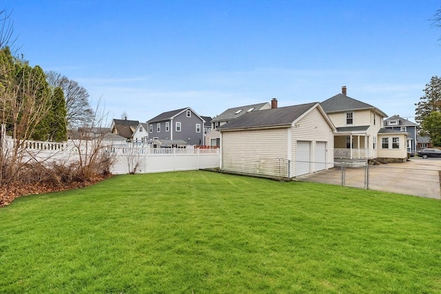 view of yard with fence, a residential view, and a detached garage
